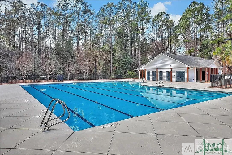 A large blue swimming pool with a diving board in front of a small building.