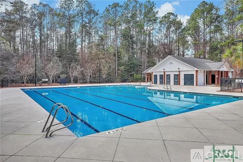 A large blue swimming pool with a diving board in front of a small building.