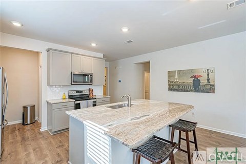 A kitchen with a marble countertop and a painting on the wall.