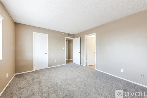 A spacious room with carpeted floor and three doors.