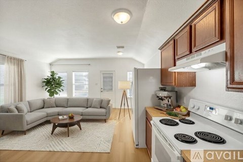 A modern kitchen with a stove top oven and a grey sectional sofa.