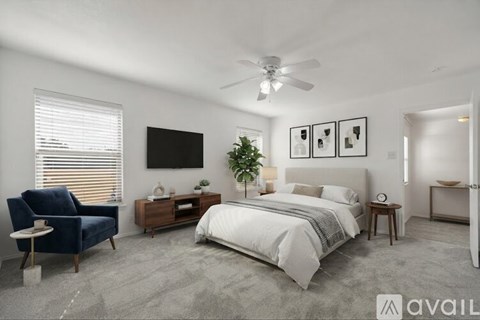 A bedroom with a bed, chair, and a ceiling fan.