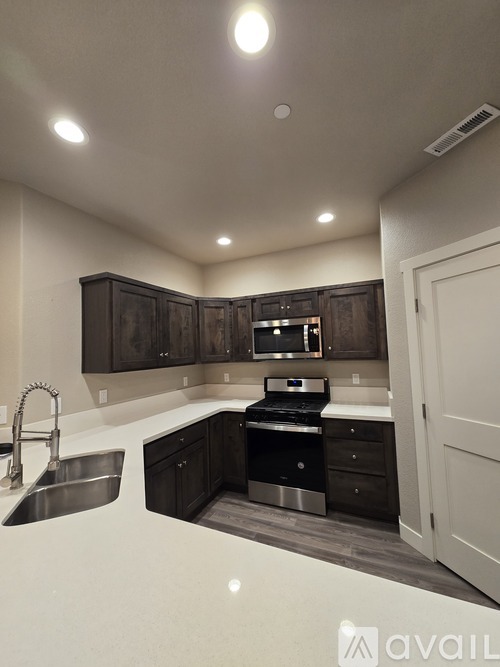 A kitchen with dark brown cabinets and stainless steel appliances.