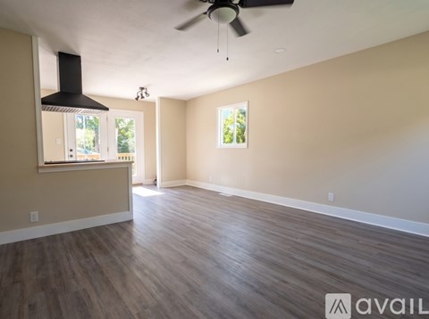 A spacious room with a ceiling fan and hardwood flooring.