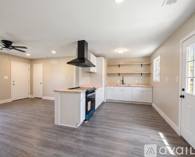 A spacious kitchen with a fan and a stove top oven.