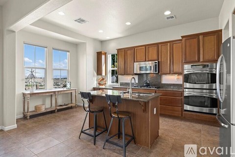 A kitchen with brown cabinets and a large island with a sink.