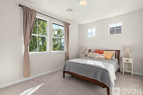 A bedroom with a large bed and a window with curtains.