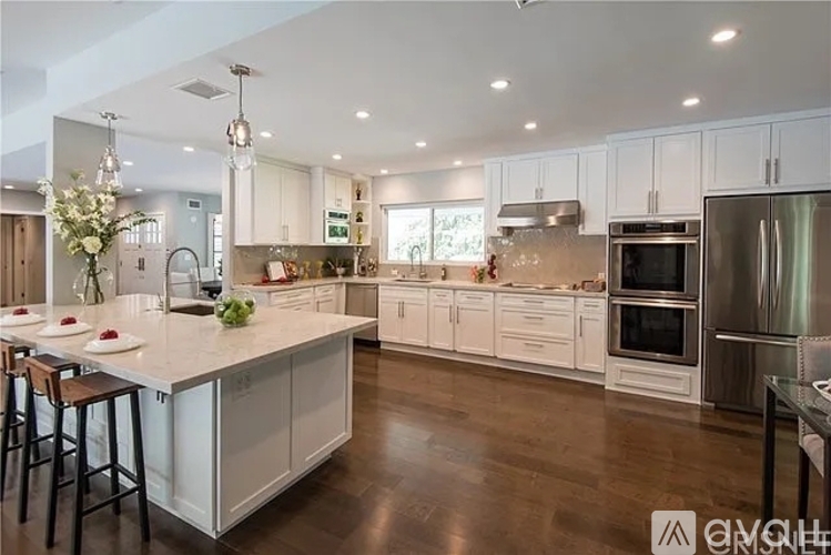 A modern kitchen with white cabinets and stainless steel appliances.