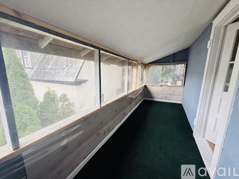 A room with a long wooden floor and a view of trees through the windows.