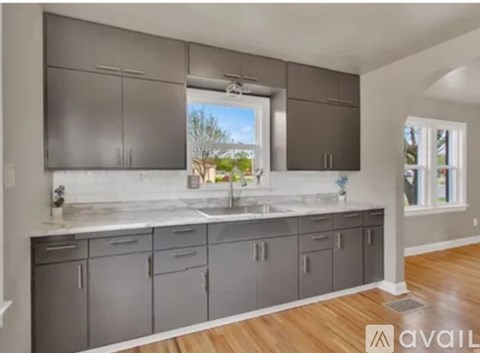 A modern kitchen with grey cabinets and a large window.