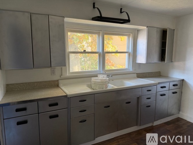 A kitchen with grey cabinets and a window.