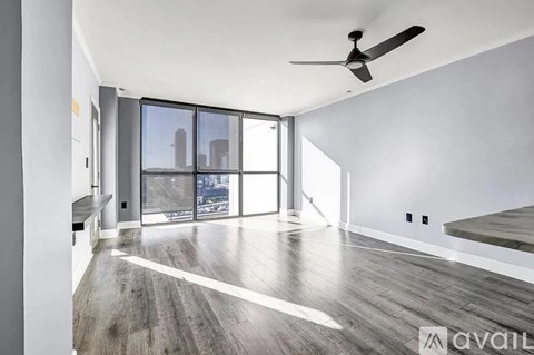 A spacious room with a ceiling fan and a view of the city through the windows.