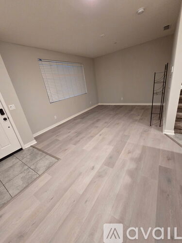 A room with light grey walls and wooden flooring with a ladder on the right side.