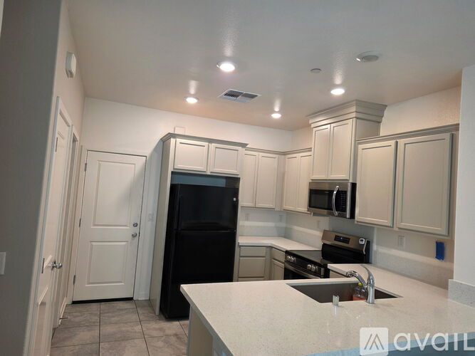 A kitchen with a black refrigerator, stove, and microwave.