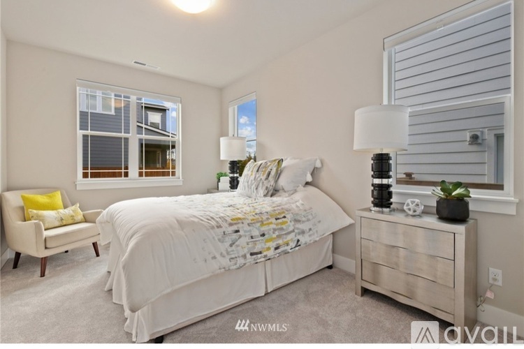 A bedroom with a large bed, a chair, and a nightstand with a lamp.
