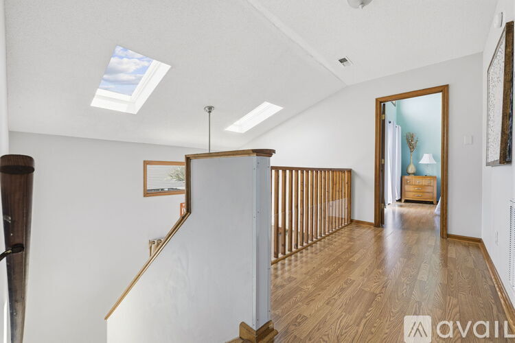 A spacious room with wooden floors and a skylight.