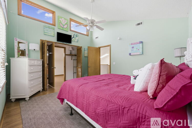 A bedroom with a pink bed and a white dresser.