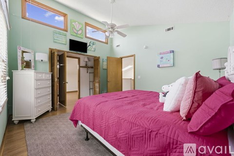 A bedroom with a pink bed and a white dresser.