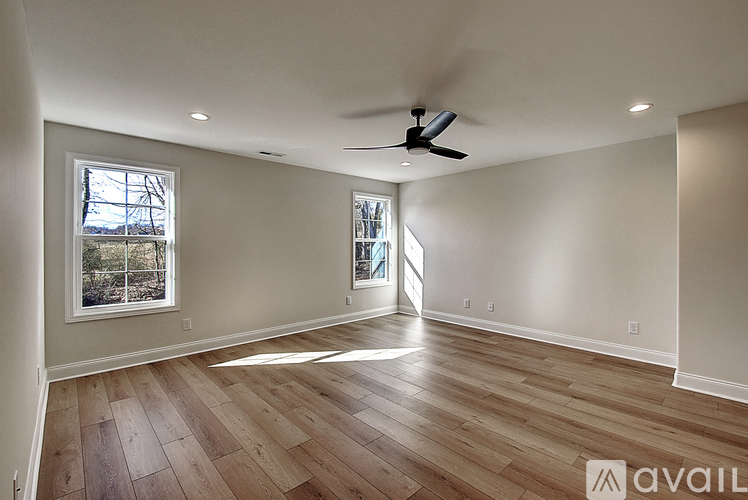 A spacious room with wooden flooring and a ceiling fan.