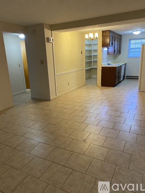 A tiled kitchen and living room area with a cabinet and a fridge.