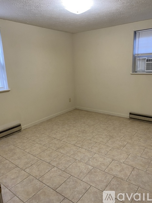 A room with tiled flooring and a window with blinds.