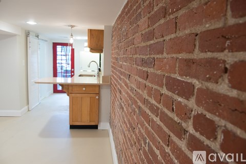 A kitchen with a brick wall and wooden cabinets.