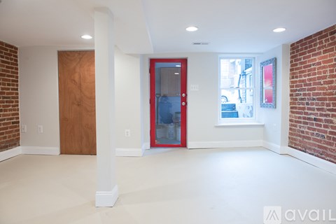 A room with a red door and a window with a view of a building outside.