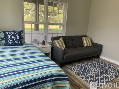 A bedroom with a bed and a couch with a pillow.