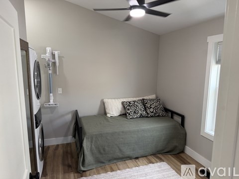 A bedroom with a bed, pillows, and a washing machine.