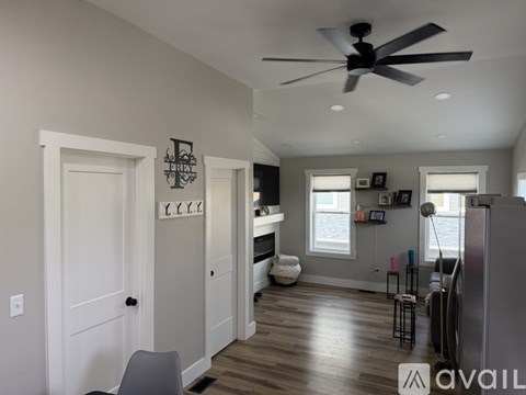 A living room with a ceiling fan and a white door.