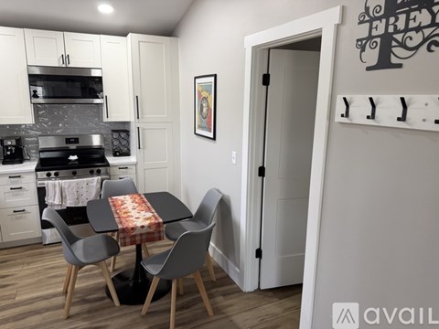 A kitchen with a table and chairs in front of a fridge.