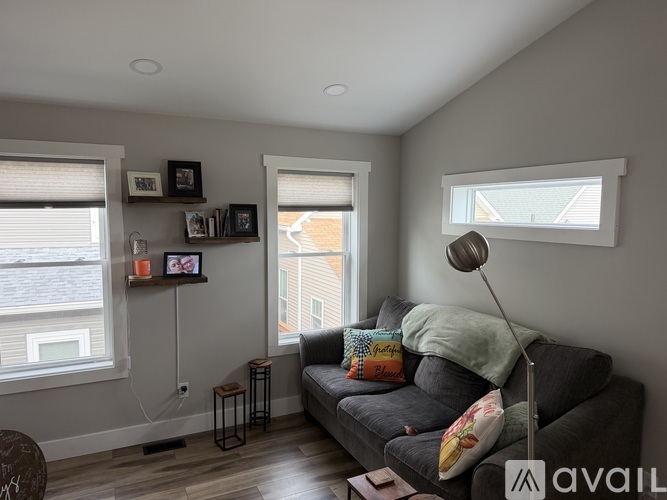 A living room with a grey couch and a lamp.
