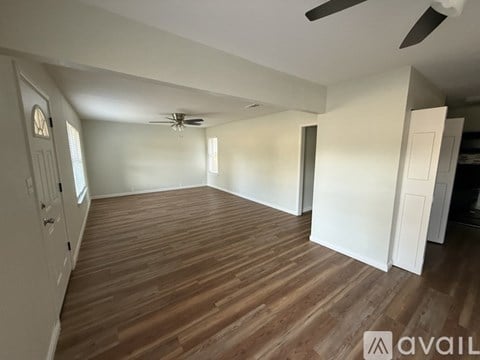 A spacious room with wooden flooring and a ceiling fan.