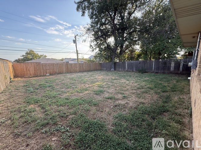 A backyard with a wooden fence and a grassy area.