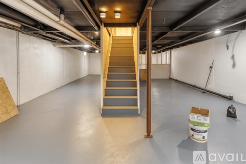 A spacious basement with a staircase and a box on the floor.