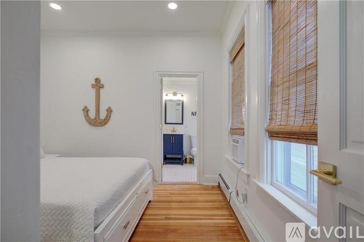 A bedroom with a white bed and a wooden floor.