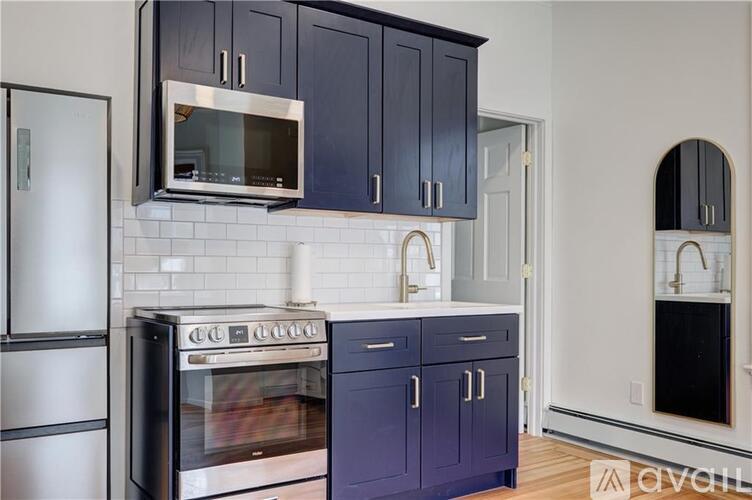 A kitchen with dark blue cabinets and stainless steel appliances.