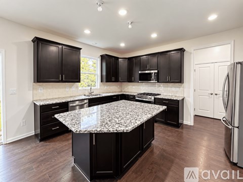 A kitchen with black cabinets and a granite countertop.