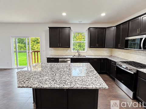 A kitchen with granite countertops and black cabinets.