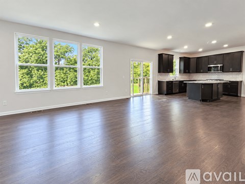A spacious room with wooden floors and large windows.