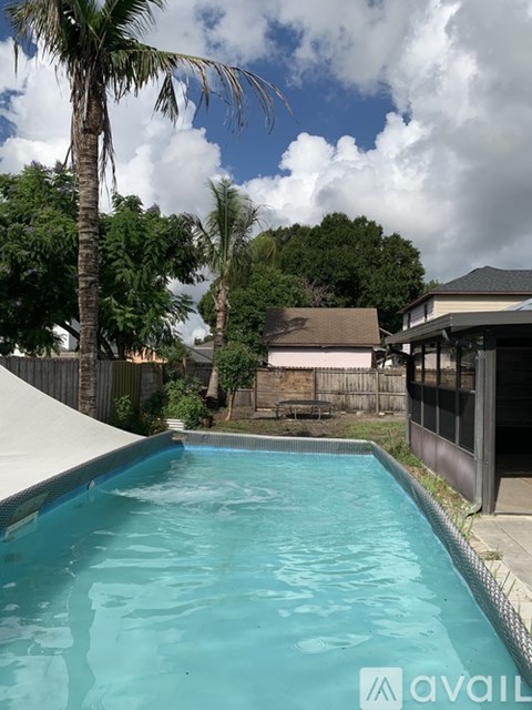 A pool surrounded by trees and a house.