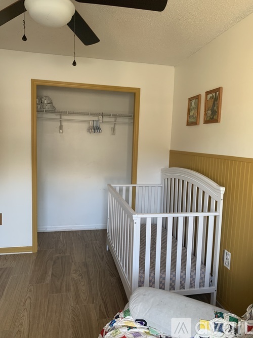 A baby room with a white crib and a ceiling fan.