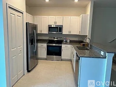 A kitchen with white cabinets and a black fridge.