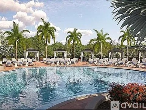 A pool surrounded by palm trees and lounge chairs.