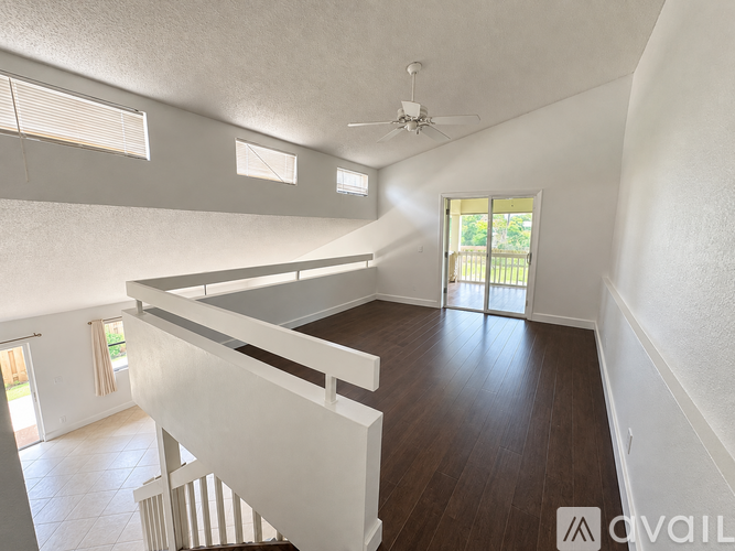 A spacious room with a staircase and a ceiling fan.