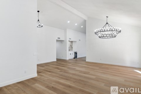 A spacious room with wooden floors and two hanging light fixtures.