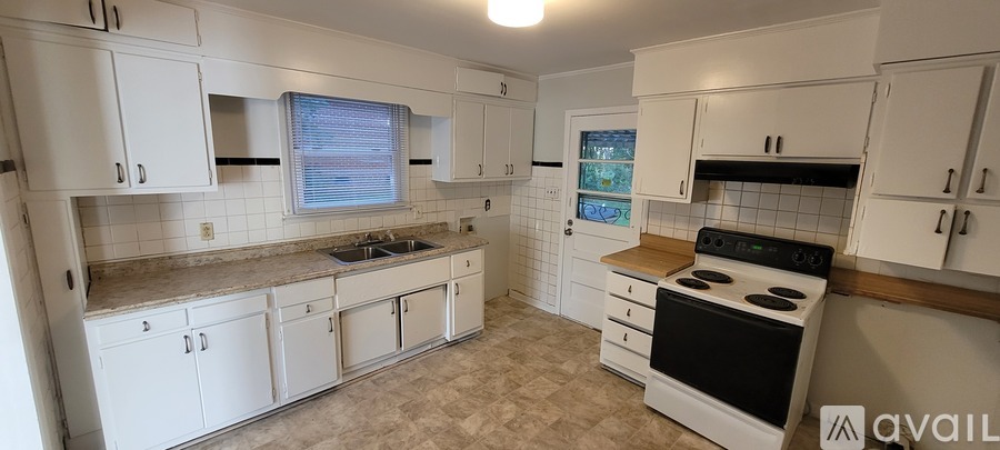 A kitchen with white cabinets and a black stove top oven.
