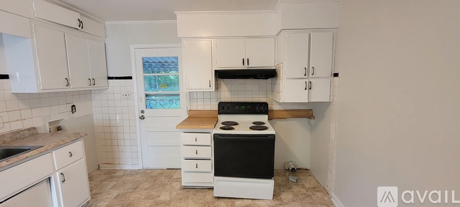 A kitchen with white cabinets and a black stove top oven.