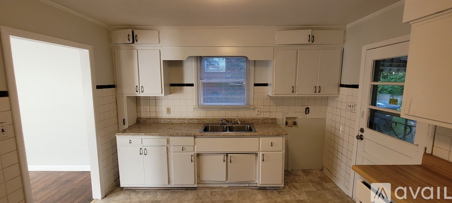 A kitchen with white cabinets and a window above the sink.