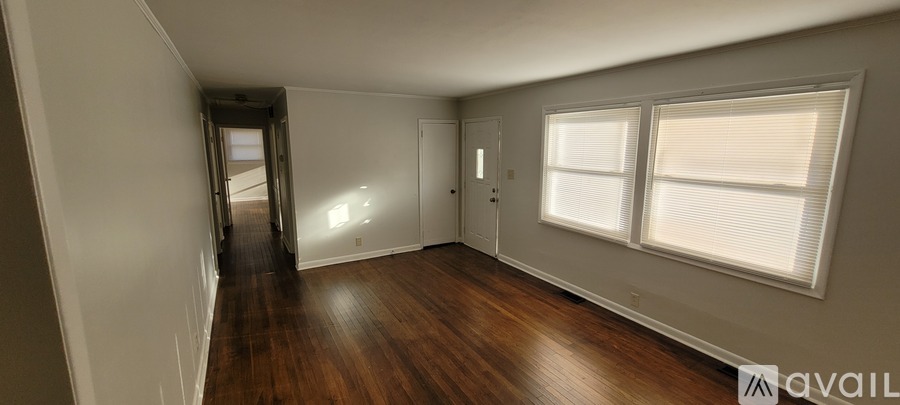 A long hallway with a door on the left and a window on the right.